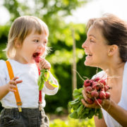 maman et enfant croquant radis dans un jardin